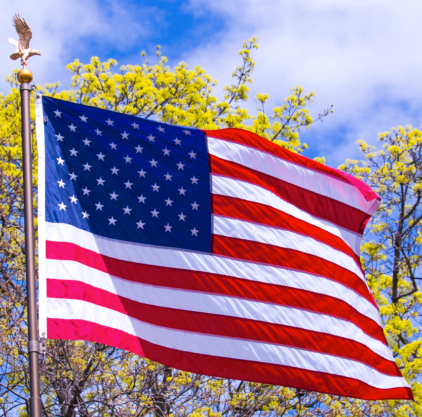 Historic gold telescoping flagpole kit by Atlantic Flagpole, featuring an American flag on a sunny day.