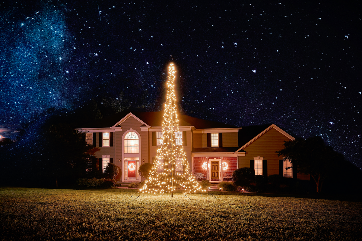 LED Christmas tree for flagpole by Atlantic Flagpole, illuminated with warm white lights, set against a night sky.